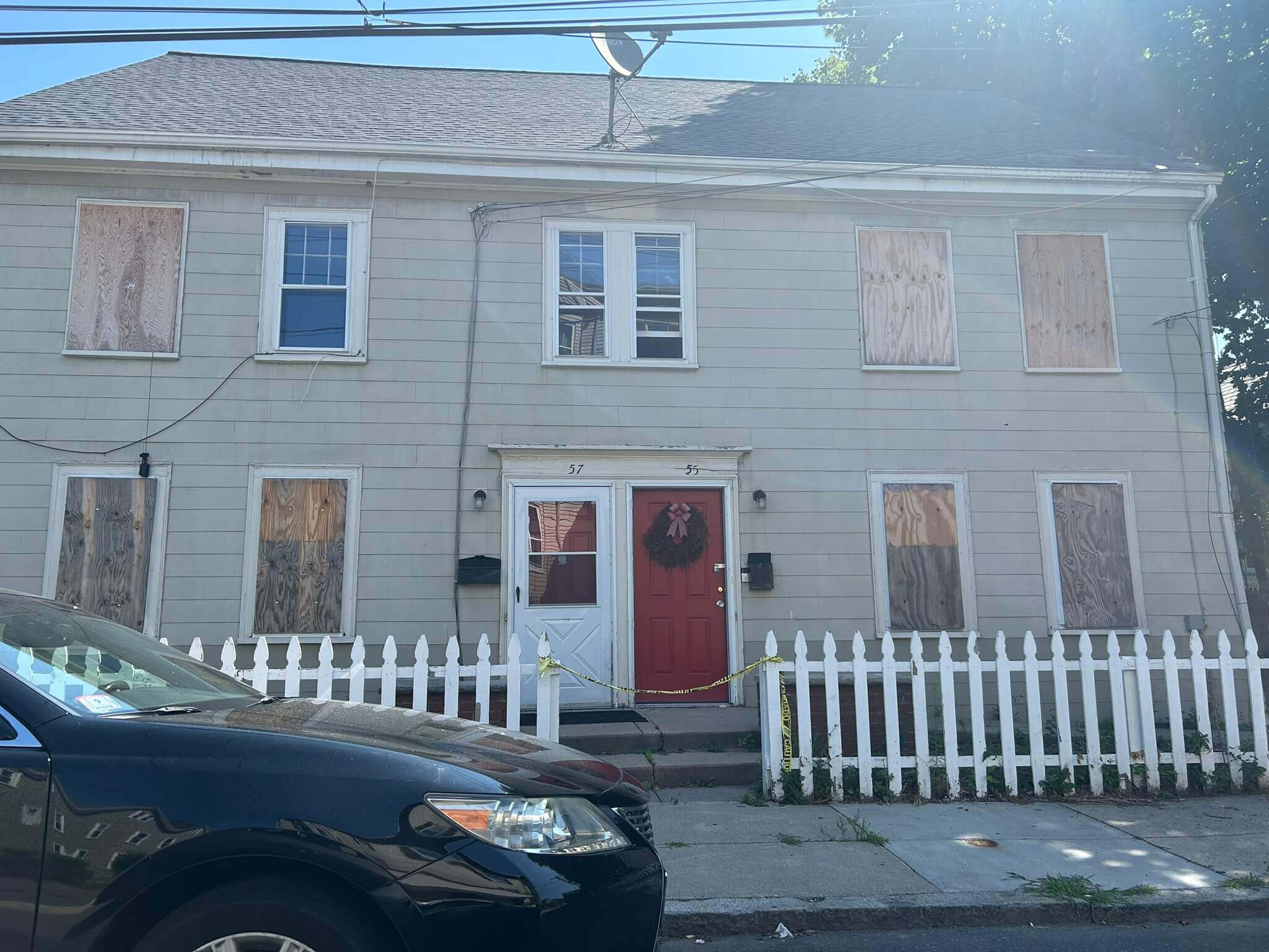 Boarded-up house with red door.